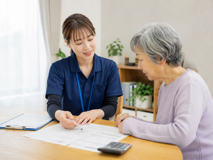 訪問看護師が利用者へ料金や保険について書類を用いて説明している様子